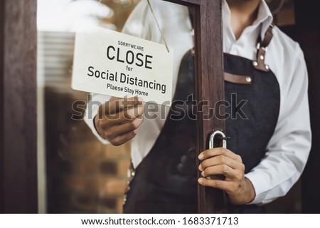Store owner turning close sign broad through the door glass for social distancing prevent corona virus outbreak. Royalty-Free Stock Photo #1683371713