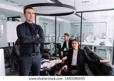 A businessman in office, colleagues in background having a discussio