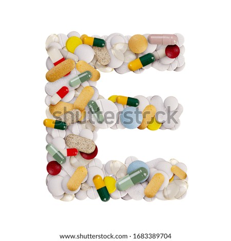 Capital letter E made of various colorful pills, capsules and tablets on isolated white background