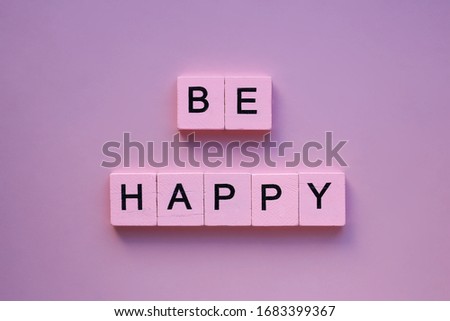 Be happy word wooden cubes on a pink background