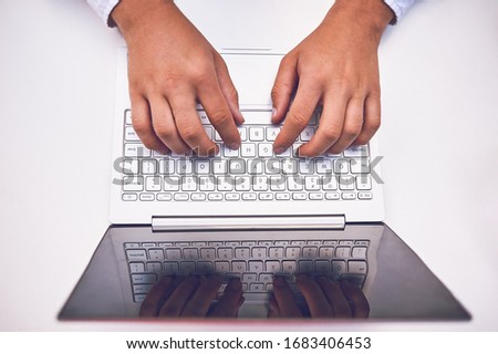 Man hand on laptop keyboard with blank screen monitor.