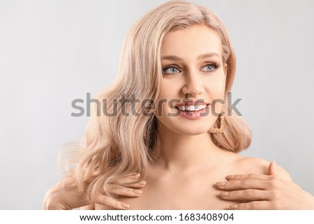 Young blonde with beautiful hair on light background