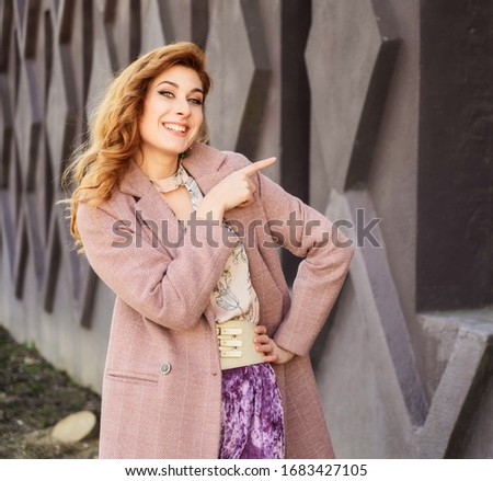 Photo of fashionable glamorous Beautiful woman with long hair in the spring city in the sun in the open air on the background of the building