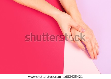 female  manicure. Beautiful young woman's hands on color pink  background