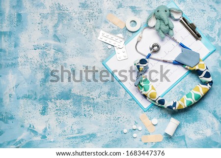 Stethoscope with cover, toy, cardiogram and supplies on color background