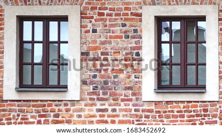The facade of an old brick building with windows or cornices. Old brick walls