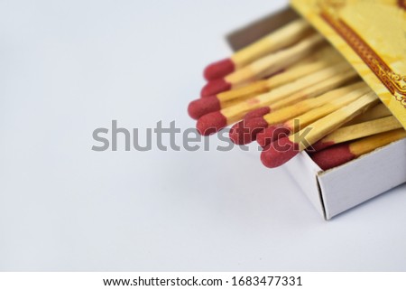Close up picture of some flammable red fire matches gathered in a small match box before white background