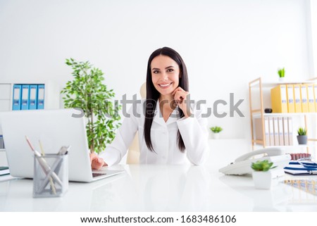 Photo of beautiful doc lady use modern technology notebook table listen patient friendly smile noting symptoms wear stethoscope white lab coat sit chair office clinic indoors