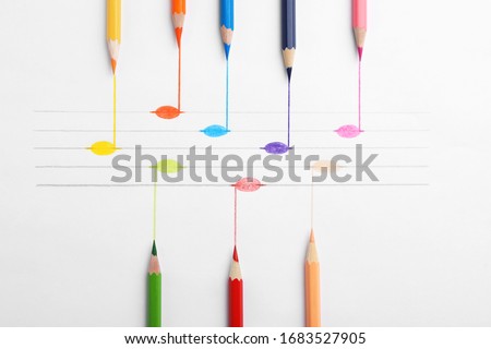 Drawing of musical notes and colorful pencils on white background, top view