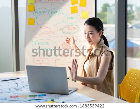 Asian beautiful entrepreneur working and talking video online with laptop and chart board in office or home desk, work at home and social distancing protect coronavirus or covid-19 health care concept Royalty-Free Stock Photo #1683539422