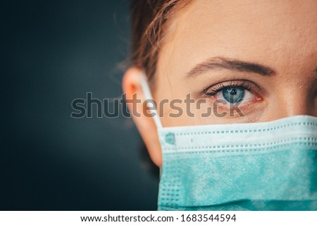 Close up portrait photo, Eye of Yong Female Doctor. Protection against contagious disease, coronavirus, hygienic face surgical medical mask to prevent infection. Black background Royalty-Free Stock Photo #1683544594