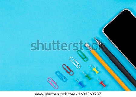 Different office supplies and tablet with a phone for work and education on a blue background