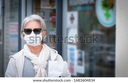 Senior lady wearing medical mask and protective gloves to prevent coronavirus infection goes to pharmacy - stop the infection, covid-19 and stay home. Concept of elderly person and fear of contagion