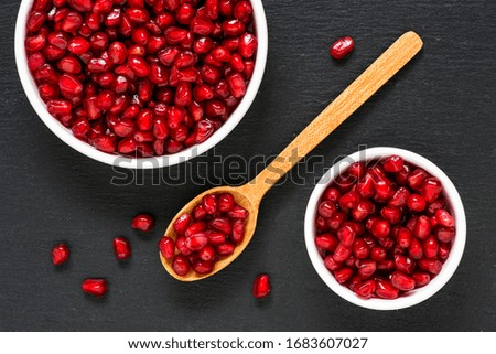 Delicious seeds of pomegranate on black slate stone background. Top View.