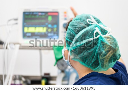 Covid-19 outbreak. Healthcare worker. Nurse working in intensive care unit. Mechanical ventilation system in the background . Royalty-Free Stock Photo #1683611995