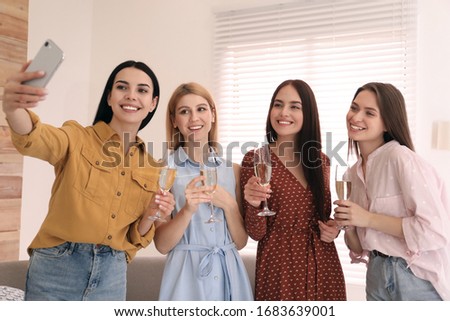 Beautiful young ladies with champagne taking selfie at home. Women's Day