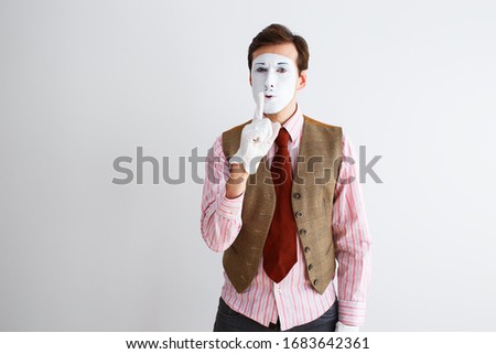 Portrait of man, actor, pantomime, man making finger gesture quieter. Emotions, facial expressions, feelings, body language, signs. Image on white studio background