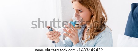 panoramic shot of asthmatic woman using inhaler with spacer Royalty-Free Stock Photo #1683649432