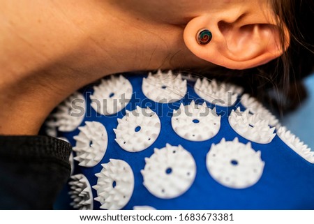 Caucasian female neck on acupressure mat in home self acupuncture massage. Close-up of white woman neck on a blue pillow with thin needles inserted into the body. Alternative medicine. Royalty-Free Stock Photo #1683673381