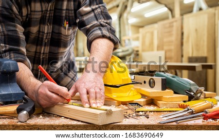 Close-up. Carpenter with pencil and the meter marks the measurement on a wooden board. Construction industry, carpentry workshop. Royalty-Free Stock Photo #1683690649