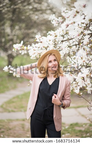 Beautiful girl next to the blossom magnolia tree. Woman is smelling magnolia buds.