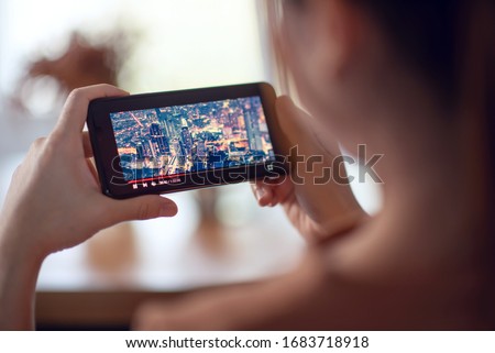 Online movie stream with smartphone. Woman watching film on mobile phone with imaginary video player service.