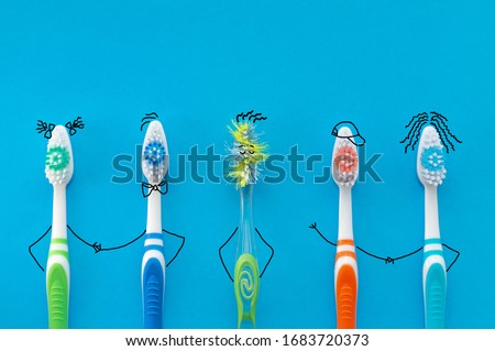Multicolored toothbrushes and an old toothbrush in the form of cartoon characters on a blue background. The view from the top. The concept of family hygiene.