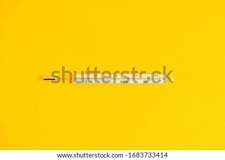 Medical mercury thermometer on a yellow background. Top view. Copy, empty space for text