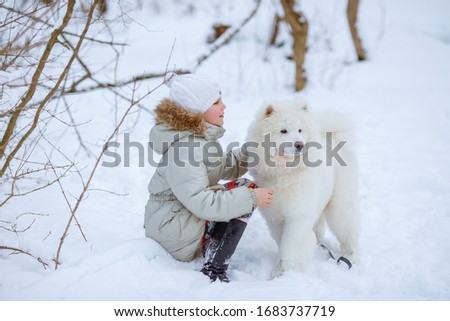 little girl child play Samoyed dog in the winter in the forest