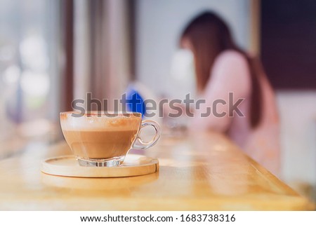 Cup of cappuccino  with blur woman background on wood table in the morning 