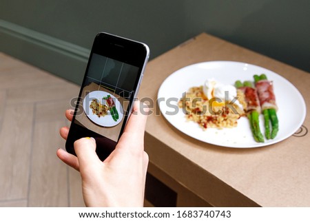 Taking a photo of porridge, vegetables, and bacon with a smartphone