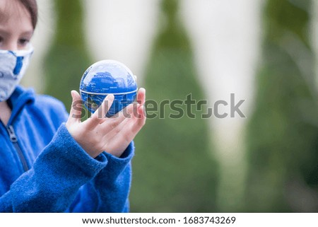 School child, holding small globe, looking sad at the world during Covid 19 pandemic, virus that spread worldwide