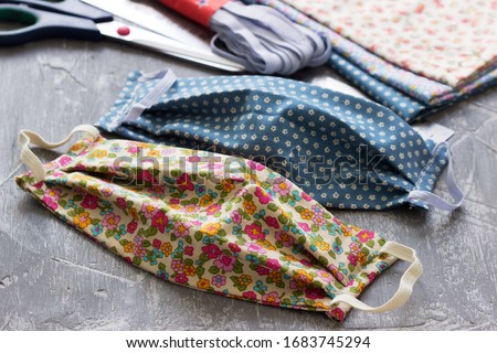 Homemade protective mask and pieces of cloth on a gray background. Royalty-Free Stock Photo #1683745294