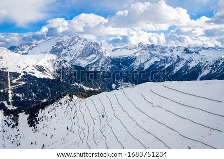Landscape at a ski resort Campitello di Fassa Italy. Winter Dolomites and blue sky with clouds. Aerial view on ski slopes and ski lifts