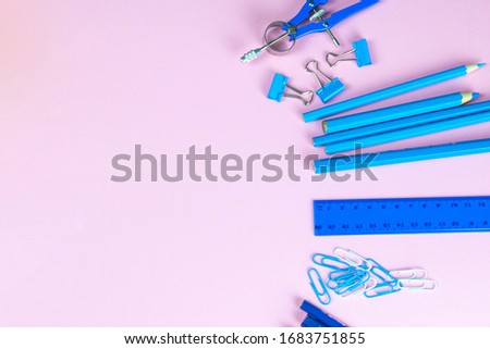 Multi-colored blue pencils rulers, pens, pencils and scissors and stationery stand on a pink background.
