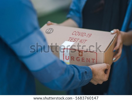 Concept for Coronavirus panic shortage of coronavirus tests to prevent the spread of the covid19. Caucasian man delivering cardboard of covid19 test kit with the mention urgent to a caucasian woman. Royalty-Free Stock Photo #1683760147