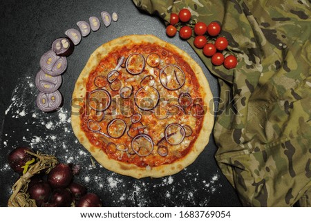 big bright tasty juicy pizza on black background. pieces of blue onions. cherry tomatoes. camouflage.