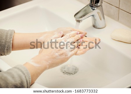 Woman cleaning hands under the running water with natural soap