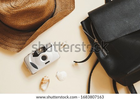 Summer holiday flat lay photo. Brown wicker hat, black backpack, camera and seashells. Travel, vacation concept