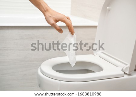 Hand throwing out toilet sheet in bowl Royalty-Free Stock Photo #1683810988