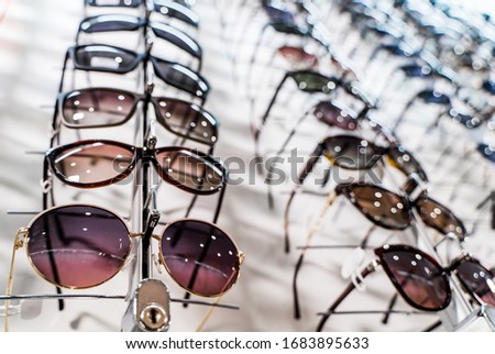 Sunglasses in the shop display shelves. Stand with glasses in the store of optics.