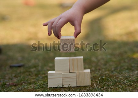 Child stacking wooden blocks in a tower or pyramid shape