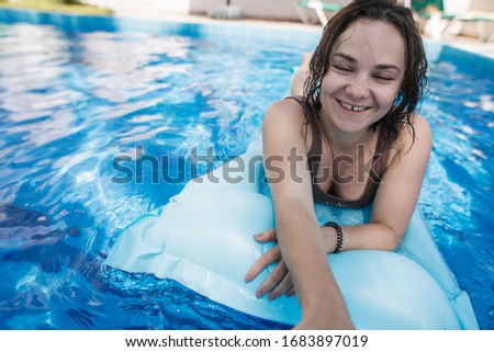 young woman relaxing in pool at villa near palm trees