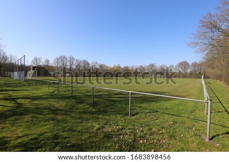 Soccer field in the Dutch rural countryside among the bare trees.Photo was taken on a sunny day with clear blue sky between winter and spring time.