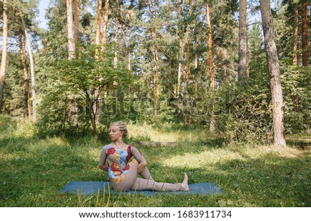 Working out yoga exercise Ardha Matsyendrasana (Half Spiral Twist Rose) on fitness mat. A young girl is engaged in a gymnastic costume.