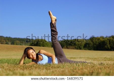 Chinese girl practicing yoga in a summer meadow.