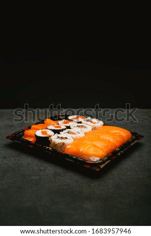 Stock photo of maki, uramaki, futomaki sushi in recycle tray on black natural slab background.
