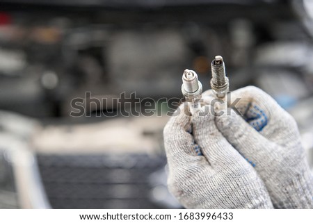 Old and new spark plugs. Comparing spark plugs the maintenance of the engine, on the hands of a mechanic.