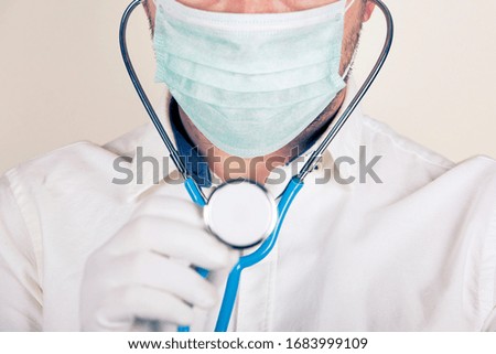 masked doctor holding a stethoscope
