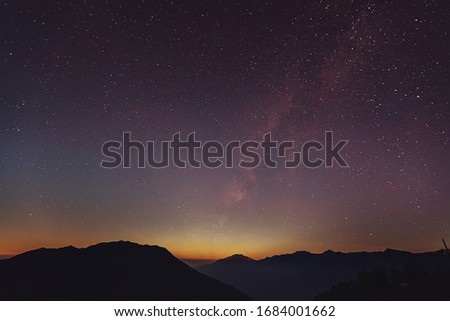 Milky Way over the mountains of the Himalayas at the time of the transition from day to night. High rocks with snowy peak and sky with stars. Night landscape with the bright galaxy in Langtang Nationa